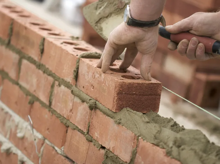 Operaio che ricostruisce un muro