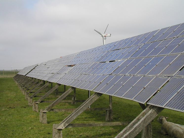 Campo con pannelli fotovoltaici e pala eolica per la produzione di energia verde