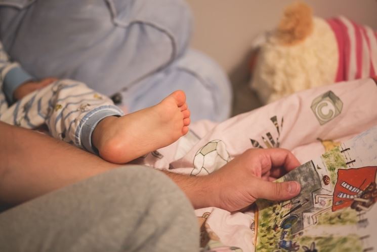 Genitore e bambino che leggono sul letto